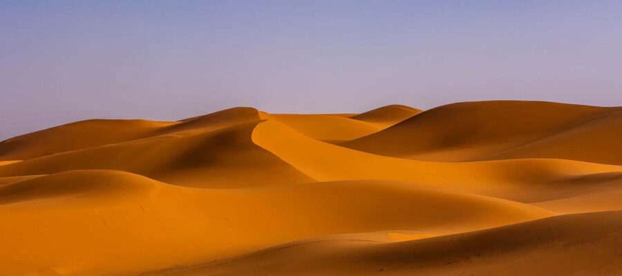 The Sahara desert in Morocco stretches out before us like an endless sea of golden sand. The dunes seem to go on forever, punctuated by the occasional acacia tree or Bedouin tent. In this vast expanse of nothingness, time stands still and the beauty of nature is on full display.